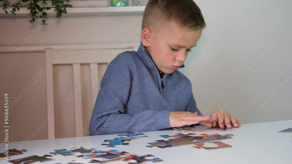 Boy collects puzzles at table. Hands of child assemble puzzle. Child development concept. Selective focus. Boy collects puzzles at table. Hands of child assemble puzzle. Child development concept. Selective focus.
