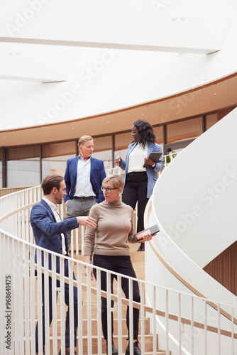 Low angle view of corporate colleagues talking while moving down on steps