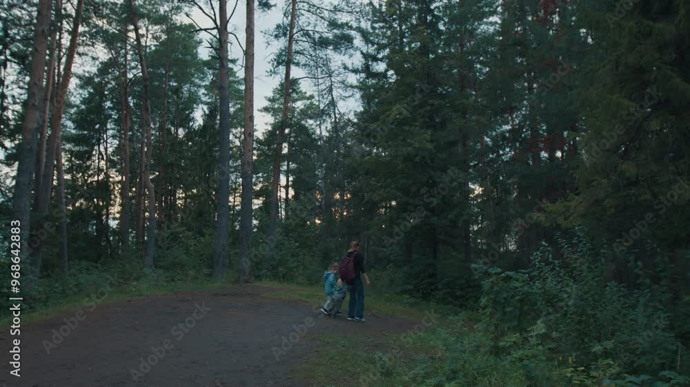 Family hiking in the dark forest. Mother with kids walk in the forest Family hiking in the dark forest. Mother with kids walk in the forest