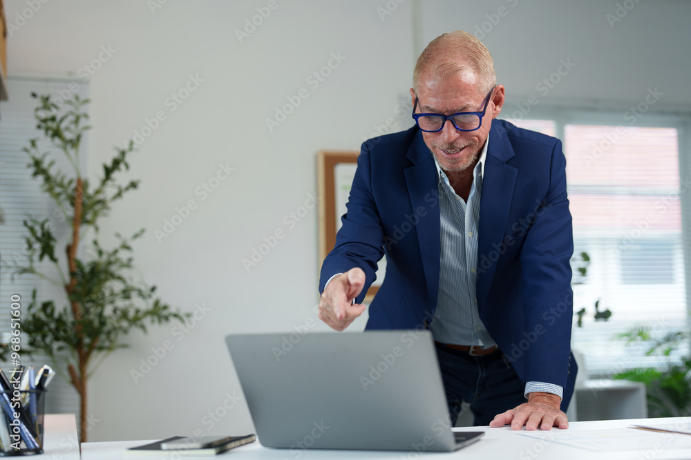 Foreign male businessman Senior man standing at desk looking at computer, business results data in office. Foreign male businessman Senior man standing at desk looking at computer, business results data in office.
