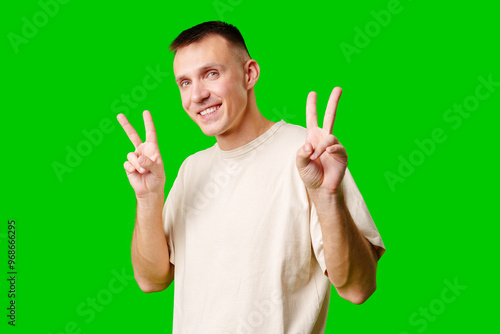 Young Man With Short Hair Making Peace Signs Against Vibrant Green Background