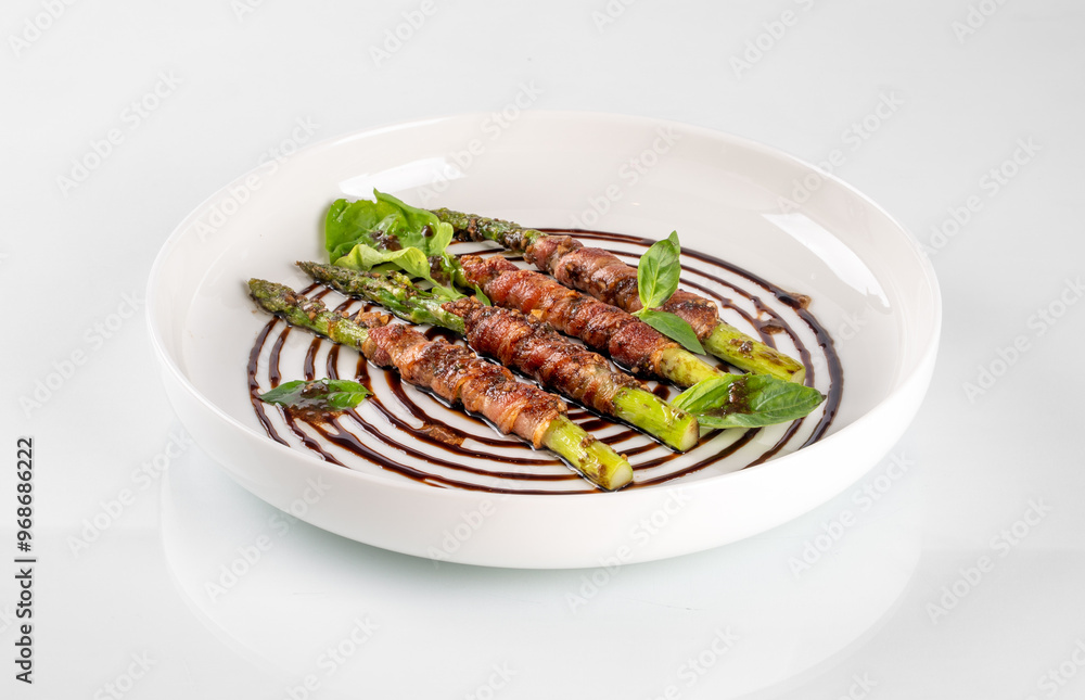 Delicious asparagus wrapped in prosciutto drizzled with balsamic reduction, elegantly plated on a white dish with herbs garnish. Delicious asparagus wrapped in prosciutto drizzled with balsamic reduction, elegantly plated on a white dish with herbs garnish.