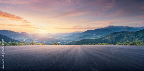 Empty asphalt road leading to distant mountain ranges and valley at sunset. High quality photo