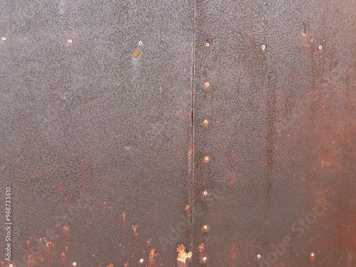 Rusty metal surface with rivets and weathered orange patina. Perfect for grunge design projects, industrial art, and vintage decor. This detailed texture provides a unique backdrop for print media photo