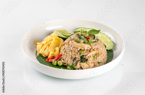 Delicious Thai fried rice served with vegetables and garnished with slices of chili, cucumber, and lime in a white bowl.