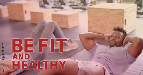 Animation of be fit and healthy text over diverse man and woman exercising in gym photo