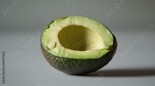 A Half-Eaten Avocado with a Pit Removed on a Gray Surface photo