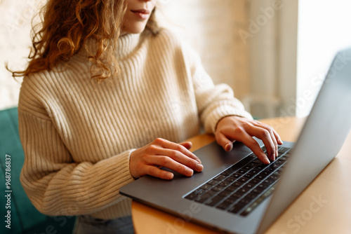 Billede på lærred Person typing on a laptop at a cozy café during the early afternoon, surrounded by a warm and inviting atmosphere