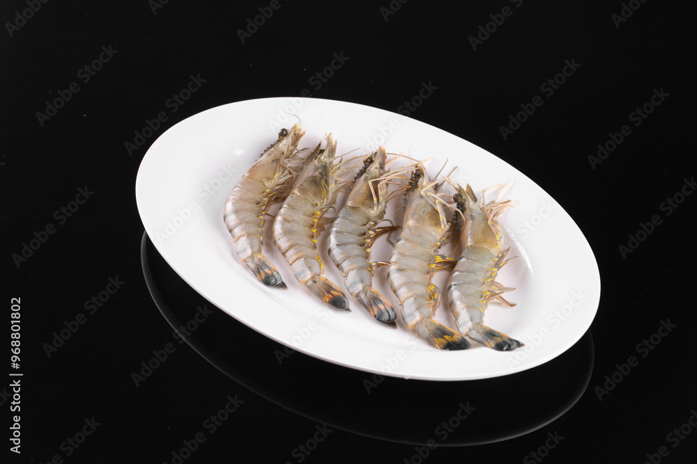 Fresh raw shrimps elegantly arranged on a white plate against a sleek black background, perfect for seafood-themed content. Fresh raw shrimps elegantly arranged on a white plate against a sleek black background, perfect for seafood-themed content.