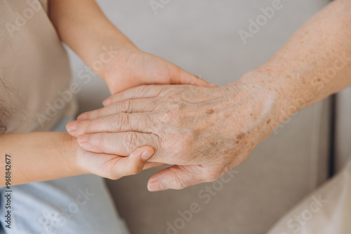 Cropped image of grandmother and granddaughter holding hands each other. Age and generation concept. Family relationship, affection, join, unity.