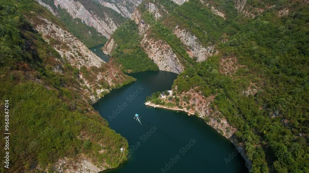 Rocky mountains reflecting on a serene mountain lake with touring boats sailing through a beautiful river valley in Albania Rocky mountains reflecting on a serene mountain lake with touring boats sailing through a beautiful river valley in Albania