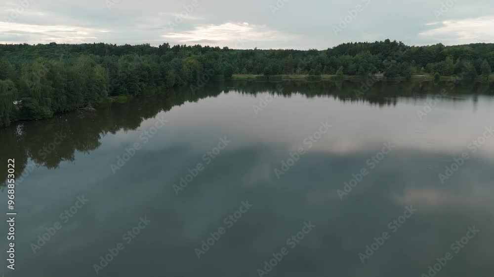 A serene lake reflects the sky and trees, creating a tranquil scene. The calm water mirrors the lush greenery and clouds, offering a picturesque and peaceful view of nature’s untouched beauty A serene lake reflects the sky and trees, creating a tranquil scene. The calm water mirrors the lush greenery and clouds, offering a picturesque and peaceful view of nature’s untouched beauty