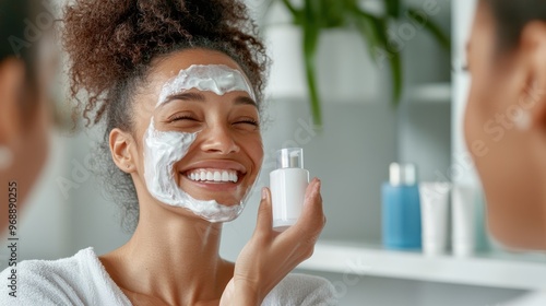 A cheerful woman with a face mask is smiling as she holds a skincare product in hand, representing joy and care in maintaining healthy skin through a beauty regimen. photo