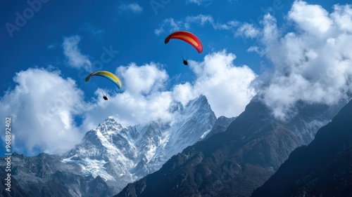 Paragliders Soaring Over Snow-Capped Mountains with Clear Blue Sky and Clouds in the Background