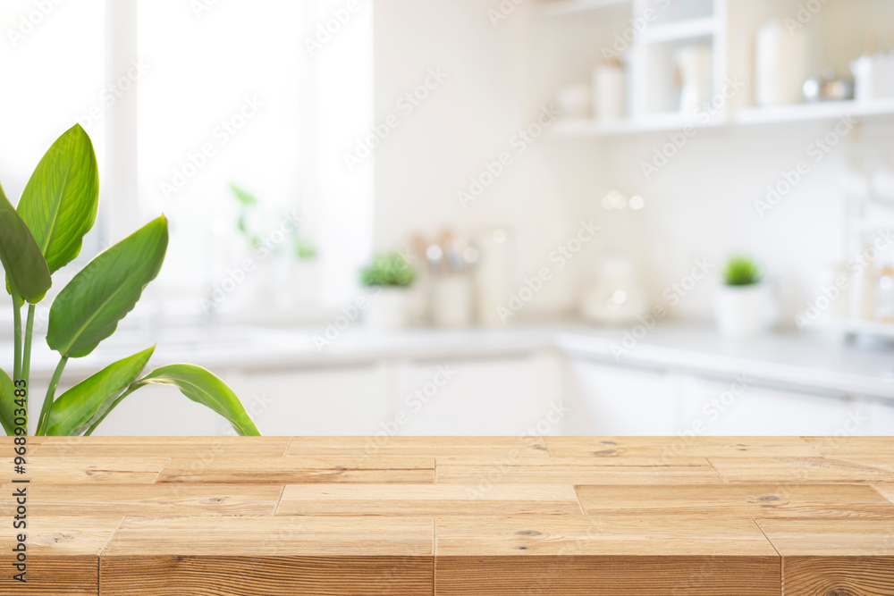 Fototapeta premium Wood table top on blur kitchen room background and green leaves for product display montage