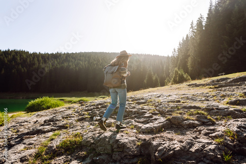 Traveler woman wearing a stylish hat and sweater enjoying a scenic lakeside landscape in the mountains during sunny autumn weather. Eco tourism. Active lifestyle. photo