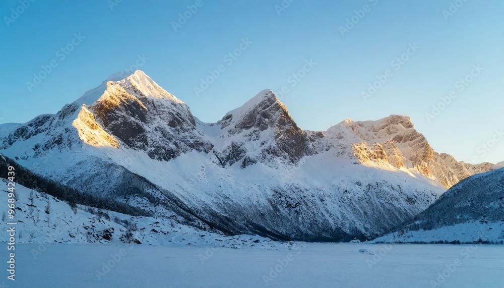 Fototapeta premium Majestic snow-capped mountain peaks under a clear blue sky in winter