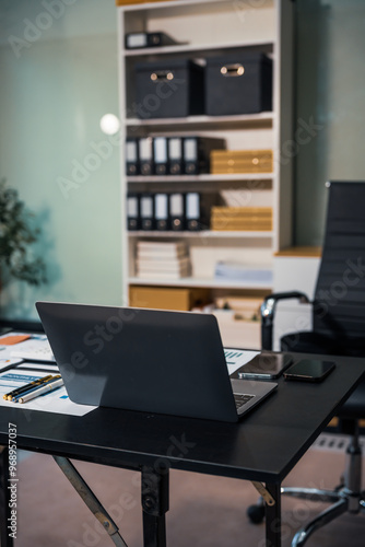 Wallpaper Mural An empty office desk at night with a laptop displaying a business chart, balance sheet, loan calculator, graphs, and monthly budget stats. Blue and black tones, leather office chair. Torontodigital.ca