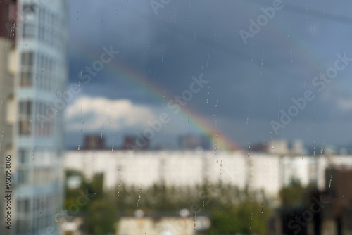 raindrops on the glass and a rainbow outside the window, the sun during the rain, a rainbow over the city photo