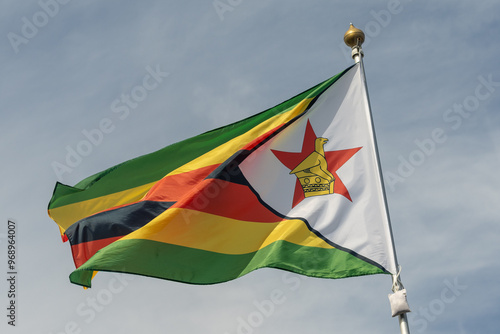 Flag of Zimbabwe, Zimbabwe, national symbol of Zimbabwe. Flag of Zimbabwe fluttering in blue sky. Independence Day. Flag of Zimbabwe, close-up. Great for news. photo