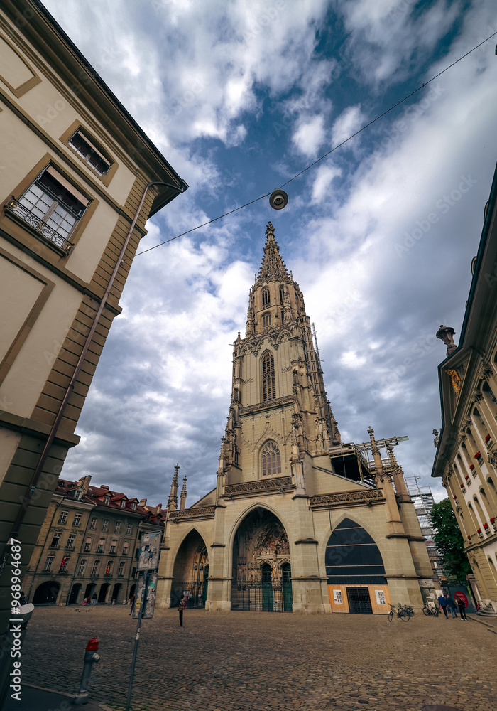Fototapeta premium Exploring the stunning architecture of the Bern Cathedral under a dramatic sky in Bern, Switzerland