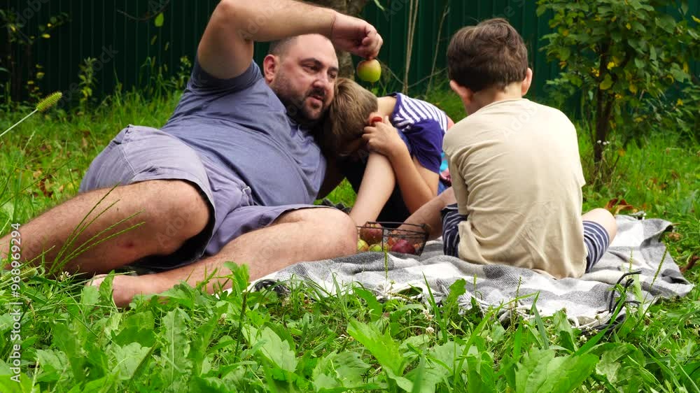 Father and sons eat and play with apples in the garden. Family time together Father and sons eat and play with apples in the garden. Family time together