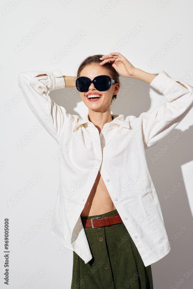 Woman with sunglasses in a stylish outfit, smiling joyfully against a plain white background, showcasing a modern fashion concept with a light and fresh vibe Woman with sunglasses in a stylish outfit, smiling joyfully against a plain white background, showcasing a modern fashion concept with a light and fresh vibe