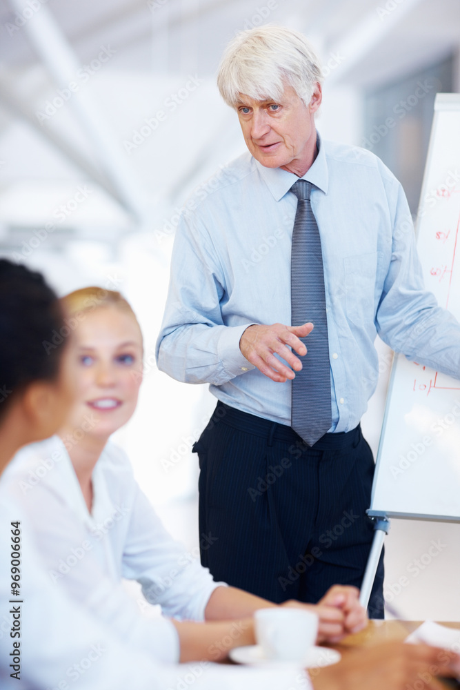 Obraz premium Mature businessman, coach and meeting with whiteboard for presentation, brainstorming or company mission. Man, executive or mentor with team or group of employees for collaboration at workplace