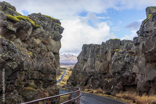 A hiker walks along a trail in Thingvellir National Park, Iceland, with the iconic rift valley between the North American and Eurasian tectonic plates in the background. photo