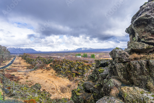 A hiker walks along a trail in Thingvellir National Park, Iceland, with the iconic rift valley between the North American and Eurasian tectonic plates in the background. photo