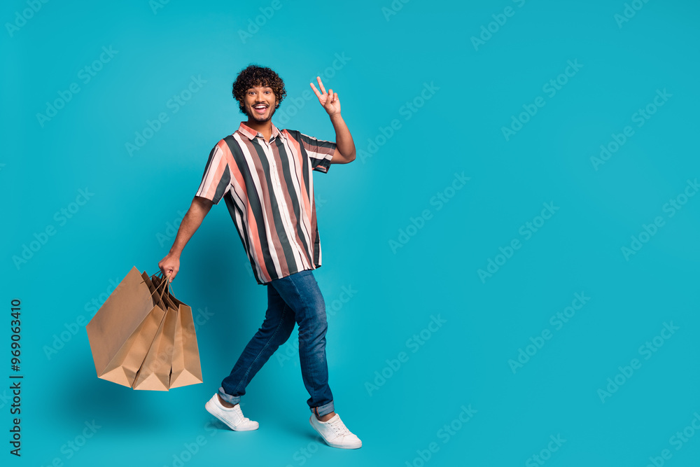 Full size photo of nice young man walk show v-sign wear shirt isolated on teal color background Full size photo of nice young man walk show v-sign wear shirt isolated on teal color background