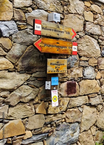 wooden boards hanging on a cut stone wall indicating the direction towards Riomaggiore and  the Sanctuary of the Madonna delle Grazie of Montenero. Genova. Italy photo