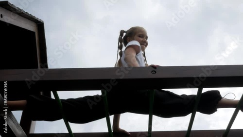 Acrobatic gymnast girl does leg stretching on the outdoors sports ground on top. Acrobatic exercise on the horizontal bar and does sports trick splits at height photo