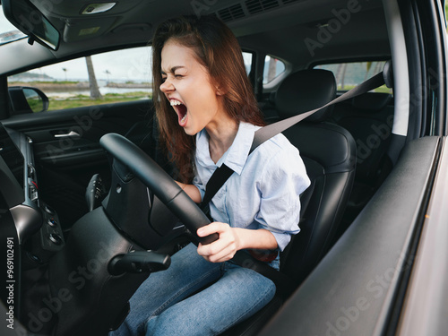 Fotografija Screaming woman driving car with hands on steering wheel, mouth wide open, sitti