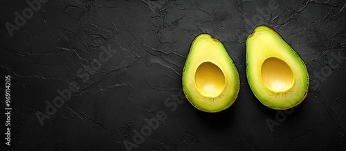 Halved avocado on a black b...