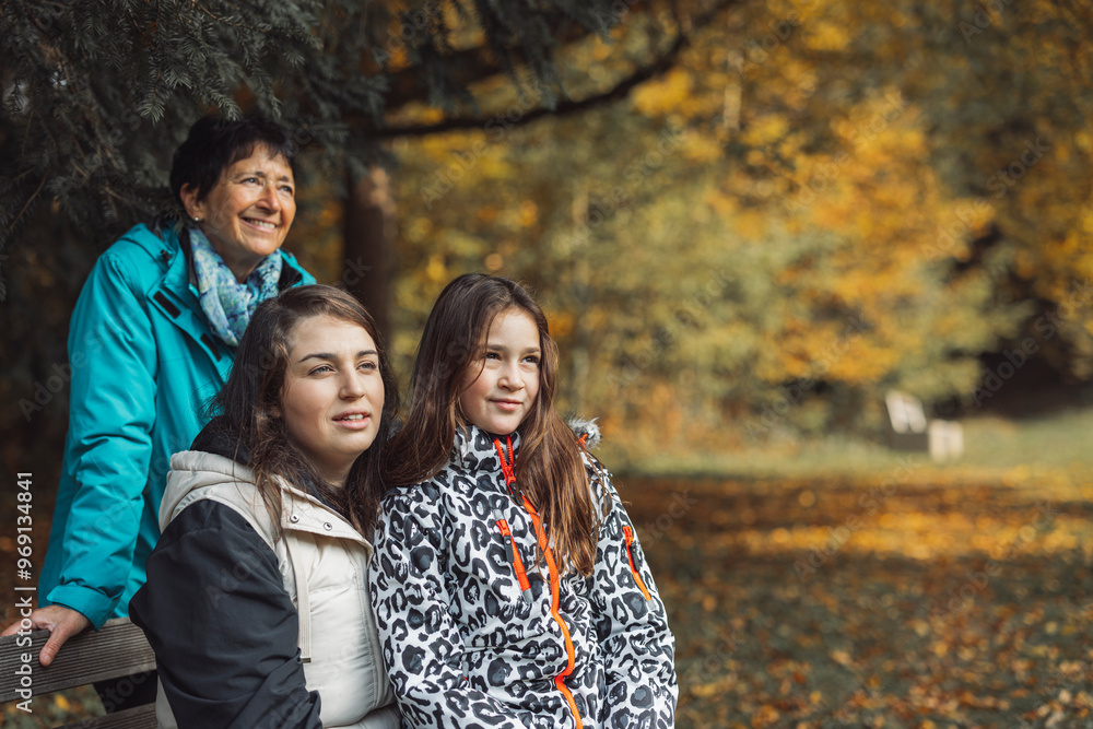 A joyful family moment in a park during autumn. Three women are sitting on a bench, laughing and enjoying each other's company amidst colorful fall foliage. A joyful family moment in a park during autumn. Three women are sitting on a bench, laughing and enjoying each other's company amidst colorful fall foliage.
