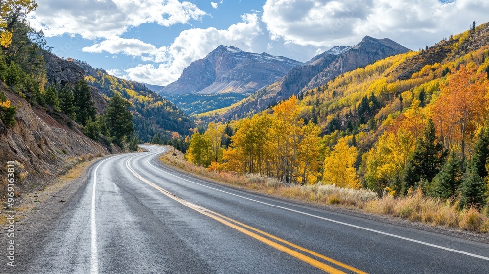 Naklejka premium A mountain road with autumn foliage lining the route, showcasing vibrant fall colors and a tranquil journey through nature.
