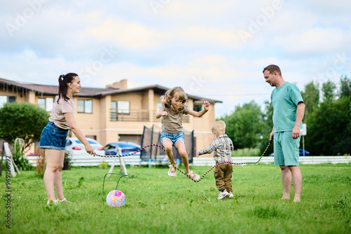 Happy family spending weekend in their backyard jumping rope and playing ball