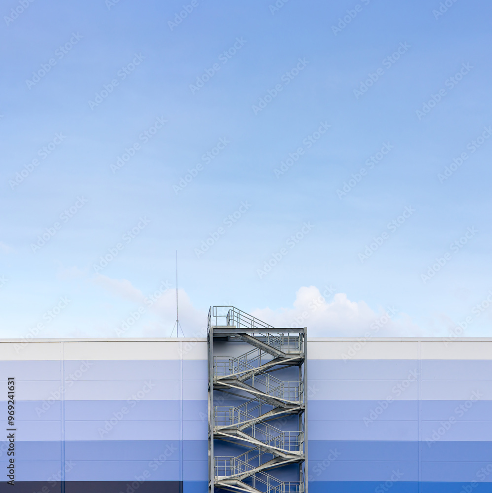 External, evacuation staircase outside the industrial hall made of sandwich panels. Photo taken on a sunny day