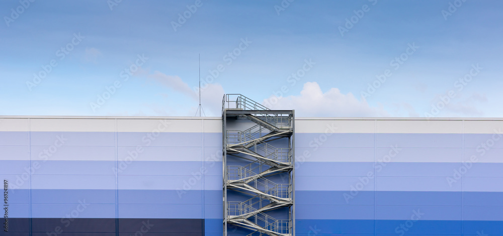External, evacuation staircase outside the industrial hall made of sandwich panels. Photo taken on a sunny day