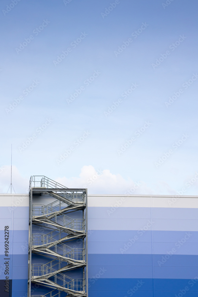 External, evacuation staircase outside the industrial hall made of sandwich panels. Photo taken on a sunny day