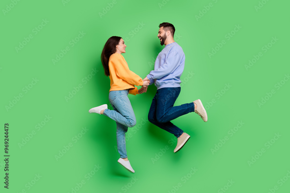 Photo of glad cheerful crazy couple wear trendy clothes have fun jump up isolated on green color background Photo of glad cheerful crazy couple wear trendy clothes have fun jump up isolated on green color background