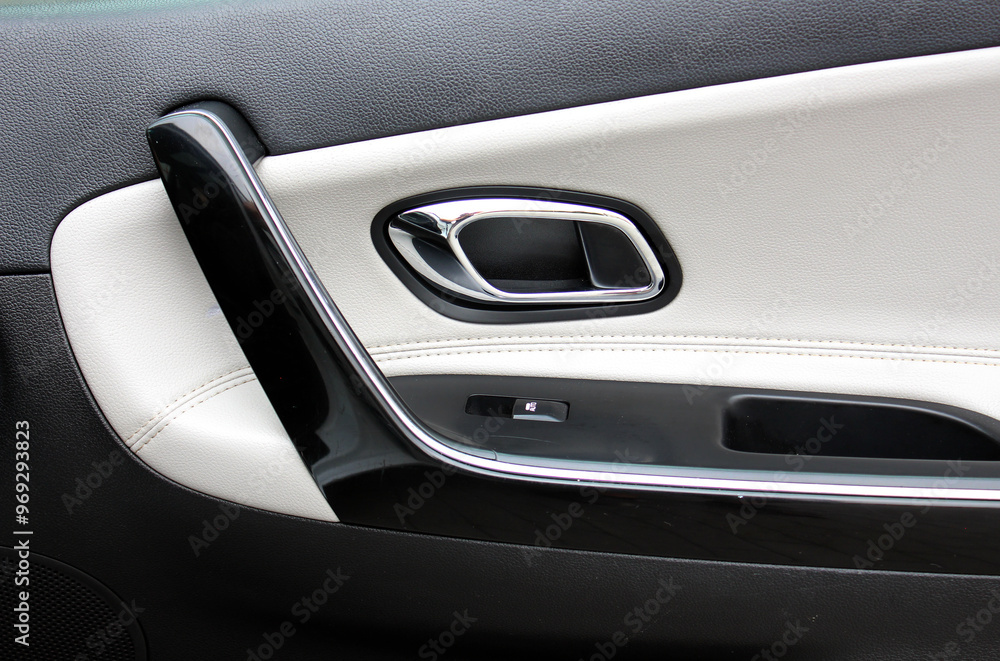 Driver lacquered Door handle with windows controls and adjustments in black white leather interior. Car leather door trim. Premium car white leather interior. Car interior details. Driver lacquered Door handle with windows controls and adjustments in black white leather interior. Car leather door trim. Premium car white leather interior. Car interior details.