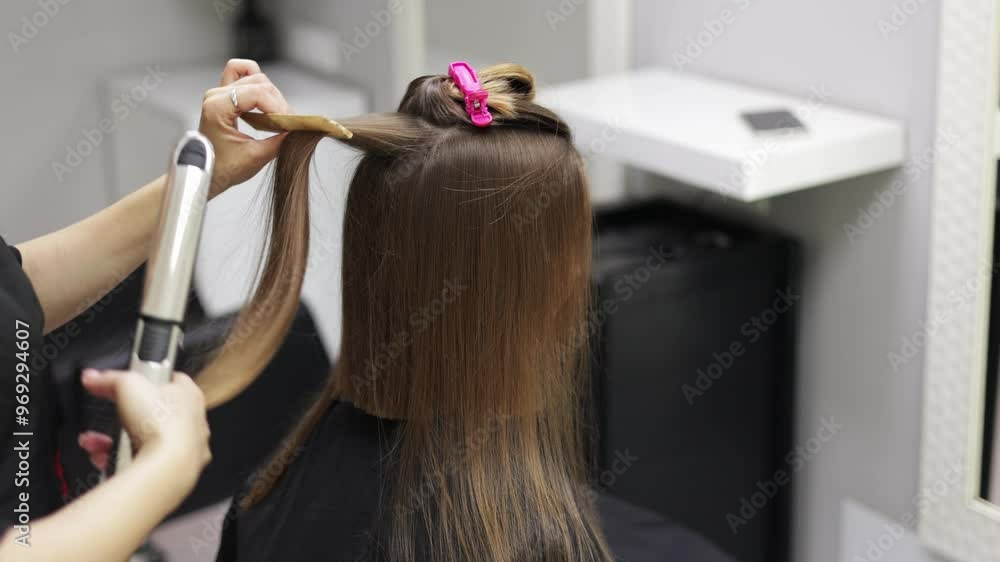 Unrecognisable professional hairdresser ironing female client hair with hair straightener and comb, making stylish hairstyle in beauty salon. Keratin, lamination,hair care, hair salon and hairstyling. Unrecognisable professional hairdresser ironing female client hair with hair straightener and comb, making stylish hairstyle in beauty salon. Keratin, lamination,hair care, hair salon and hairstyling.