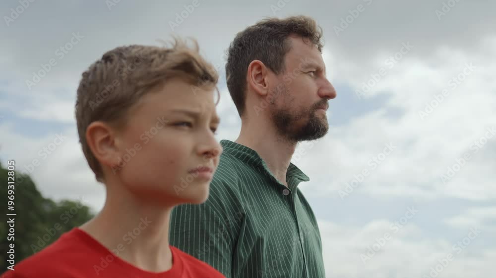 Father and teenage son take leisure walking along coastline of bay. Talking and sharing stories and jokes, smiling and enjoying togetherness. They stop to look at skyline. Family bonding Father and teenage son take leisure walking along coastline of bay. Talking and sharing stories and jokes, smiling and enjoying togetherness. They stop to look at skyline. Family bonding