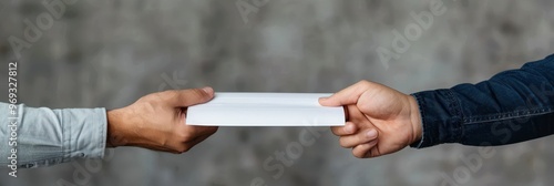 Close-up of two hands exchanging a white envelope, symbolizing communication, transaction, or agreement in an outdoor setting. photo