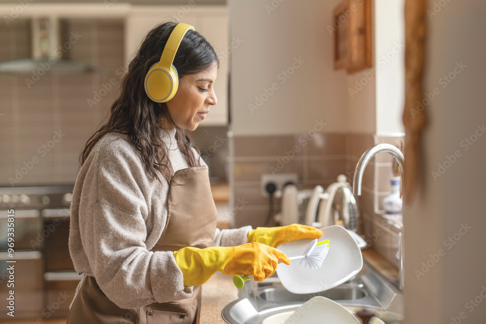 Joyful Woman Wearing Headphones Washes Dishes in Cozy Kitchen During Morning Hours Joyful Woman Wearing Headphones Washes Dishes in Cozy Kitchen During Morning Hours
