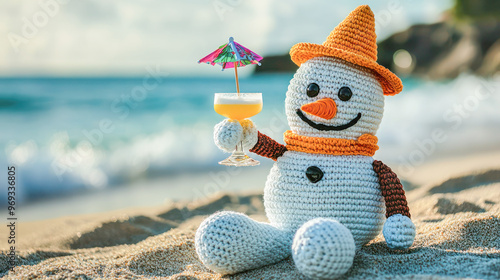 Crochet snowman in an orange hat and scarf holding a cocktail with an umbrella on a tropical beach. photo