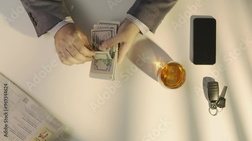Top view of man counting large wad of us dollars money banknotes, flipping through bills, taking or borrowing money in credit.