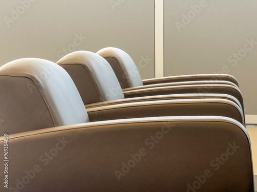 Three identical armchairs, side by side, near a divider in a car dealership, for motifs of comfort and waiting photo